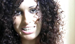 Curly-haired amateur chick strokes her vagina in the bedroom