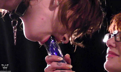 Tattooed cutie forced to suck a hard purple dildo of a dominatrix