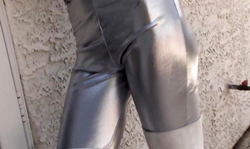 Dark-haired beauty in shiny spandex tights poses outdoors