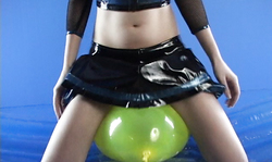 Hot-shaped young babe in black miniskirt and her green balloon