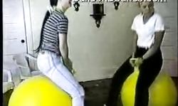 Amateur girls in tight jeans are jumping on the giant yellow balloons