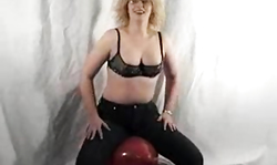 Sexy busty MILF in tight black jeans sits on a balloon